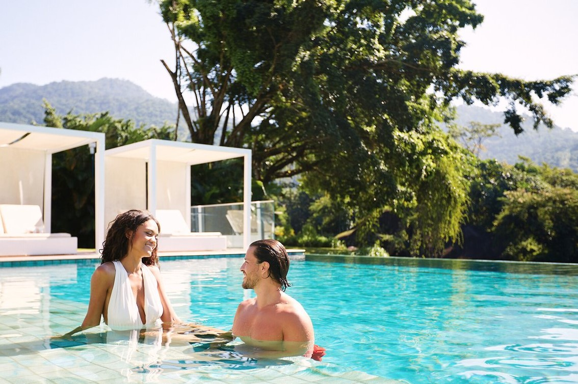 Couple relaxant dans la piscine du Club Med Rio Das Pedras avec des lits de détente sous pergolas en arrière-plan. Couple relaxant dans la piscine du Club Med Rio Das Pedras avec des lits de détente sous pergolas en arrière-plan.